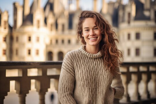 Lifestyle portrait photography of a grinning girl in her 20s smirking wearing a cozy sweater at the chateau de chambord in chambord france. With generative AI technology