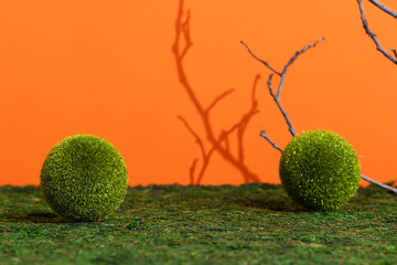 Premium empty scene with grass balls on green moss on an orange background with shadows of tree branches. Podium for product promotion, beauty, natural eco cosmetic. Showcase, display case.