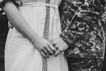 War and love. Closeup man in camouflage uniform hugging woman. Engagement. Wedding rings. Serviceman, soldier embracing wife before leaving for war. Patriotic man go serve country. Black white photo