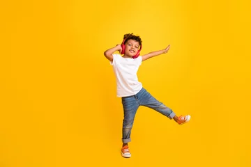 Papier Peint photo École de danse Full length photo of pretty carefree small boy wear white t-shirt having fun listening music headphones isolated yellow color background