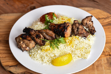 Joojeh Kebab rice or Jojeh Kabab with tomato and lime served in dish isolated on wooden table top view middle eastern lunch food