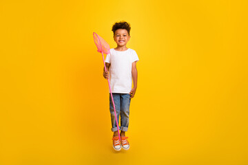Fototapeta na wymiar Full length photo of charming cute small boy wear white t-shirt holding scoop jumping high isolated yellow color background