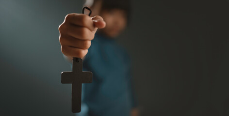 A little girl is using a cross to protect herself and holding a cross.