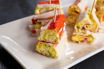 Rolls of crab sticks on a white surface. Snack.