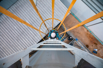 Top view male worker climbs down the ladder inspection stainless tank work at height safety