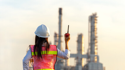 Engineer inspector construction building power plant energy industry in project site.  Woman worker holding white helmet for security control refinery plant.   Industry and Engineer Concept