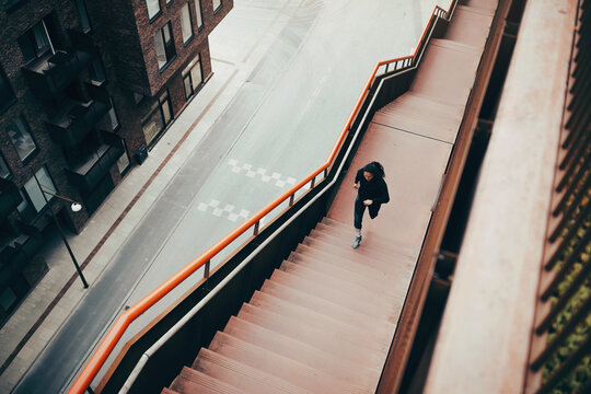 Fit young woman running up steps outdoors