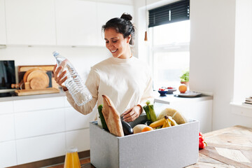 Smiling woman unpacking a box of groceries