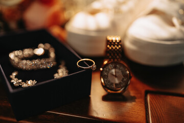 Women's jewelry on a dark background. A gold ring with a diamond on a white background. Necklace, women's wristwatch. Selective focus - obrazy, fototapety, plakaty
