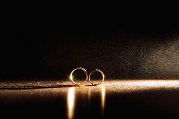 Two wedding rings in infinity sign with sparkling light mist. Love concept on black background