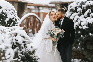 Beautiful and happy bride and groom are having fun among snowy trees. Bride and groom in the winter...