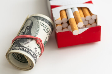 white cigarettes lying on the dollar bills. concept of financial cost of smoking.