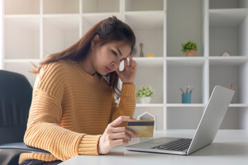 Young Asian woman stressed out paying with credit card for online shopping When faced with expensive expenses