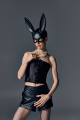 queer model in corset posing in bdsm bunny mask on grey, pearl necklace, provocative style