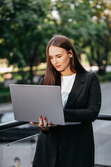 
Happy young business woman typing on a laptop. A woman in a suit is satisfied with her work and a successful deal.