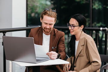 A young woman and a man are discussing their current project on the terrace. A business couple is actively discussing inflation and a planned new outdoor project.