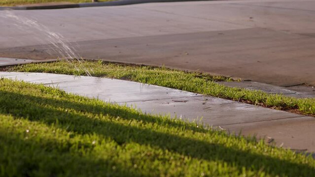 lawn sprinkler showing wasting water on the sidewalk