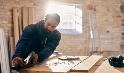 Woodworker planing wood at a workshop bench