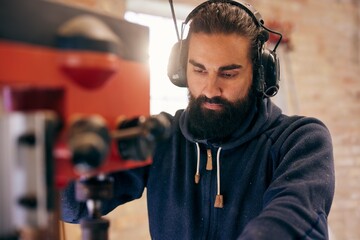 Carpenter using a drill press in his workshop