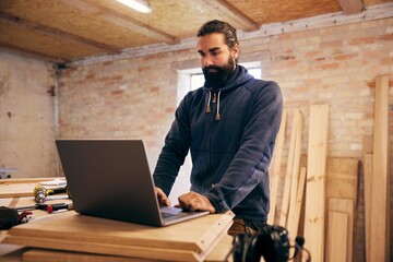 Woodworker using a laptop in his carpentry shop
