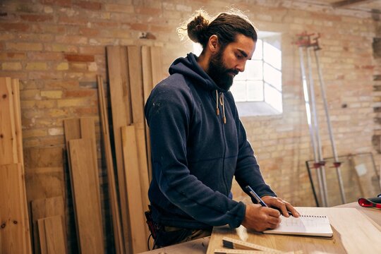 Woodworker sketching ideas at a workshop bench