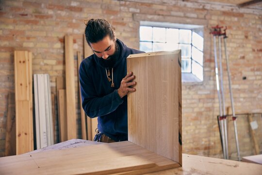 Carpenter assembling wood at a workshop bench