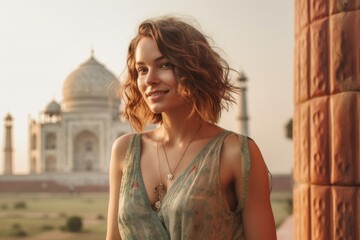Fototapeta premium Environmental portrait photography of a blissful girl in her 30s wearing a cute crop top in front of the taj mahal in agra india. With generative AI technology