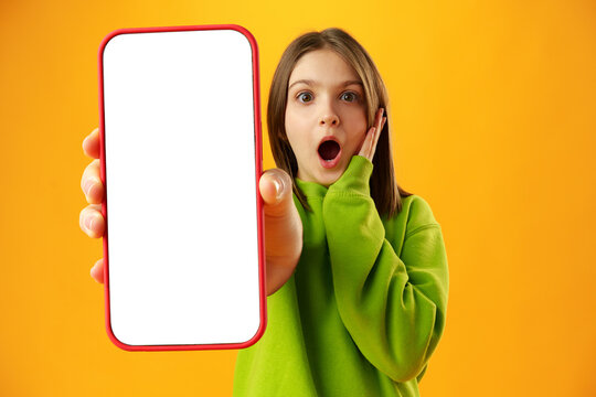 Teen girl showing smartphone screen with copy space over yellow background