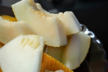 The melon is cut into pieces. On a dark background, light pieces of melon are a close shoot. Juicy melon in pieces.