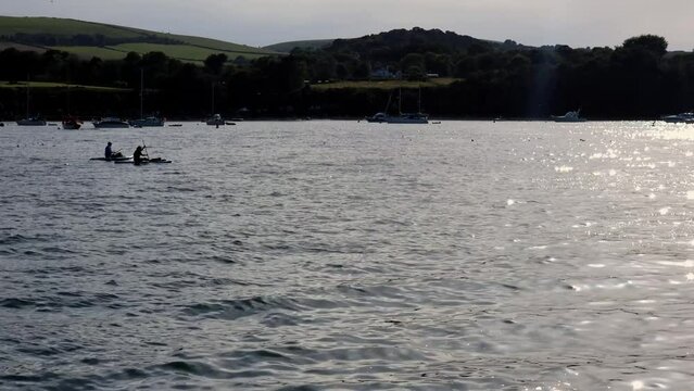 Silhouette of 2 kayakers padling across a beautiful ocean bay in Studland Dorset United Kingdom