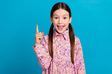 Photo portrait of pretty schoolkid point up empty space idea dressed stylish pink flower print outfit isolated on blue color background