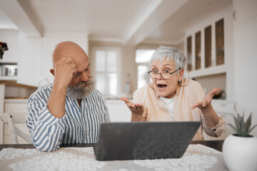 Laptop, argument and senior couple at their home for paying bills debt or mortgage online. Pension,...