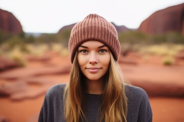 Medium shot portrait photography of a glad girl in her 20s wearing a warm wool beanie near the uluru (ayers rock) in northern territory australia. With generative AI technology