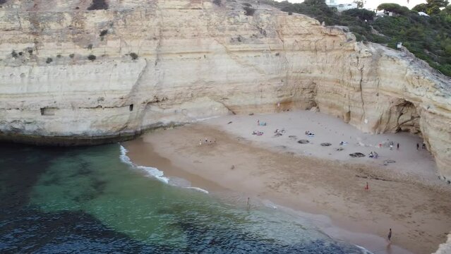 Quick Aerial Landscape Pan of Sandy Beach with People Enjoying Life. Drone from up above right pan motion with waves crashing on the sandy beach.