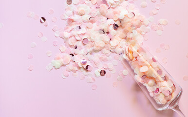 Confetti in a champagne glass on a pink background. The concept of the winter holidays - Christmas and New Year. Top view. Space for text