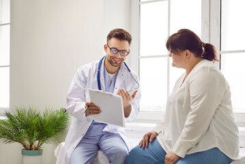 Portrait of fat overweight female patient in medical office listening to a friendly doctor holding report file with appointment and giving consultation a woman during medical examination in clinic.