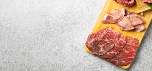 Top view Variety Fresh raw beef steaks on wooden board for grilling. hot pepper and herbs. Japanese food isolated on gray stone banner background