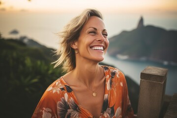 Photography in the style of pensive portraiture of a cheerful mature woman wearing a trendy off-shoulder blouse at the christ the redeemer in rio de janeiro brazil. With generative AI technology - obrazy, fototapety, plakaty