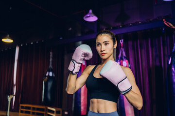 Fototapeta na wymiar Female Boxer training in Boxing Club. Woman Boxing fighters training at gym. Strong muscular woman practicing box in pink boxing gloves in gym..