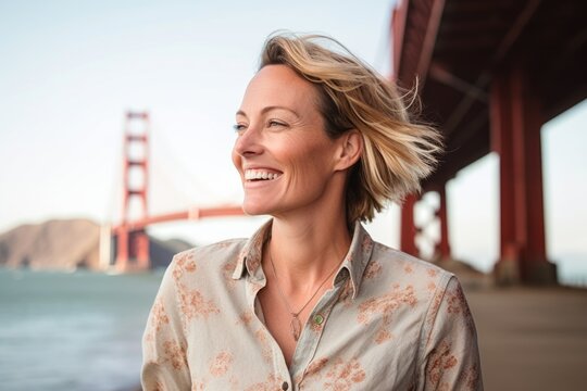 Photography in the style of pensive portraiture of a happy girl in her 40s wearing a classy polo shirt at the golden gate bridge in san francisco usa. With generative AI technology