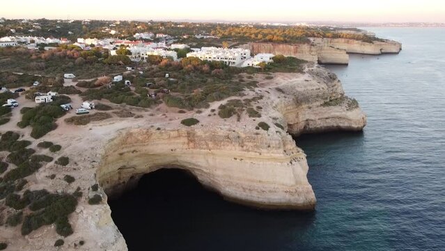 Aerial Lagoa Portugal City and Ocean Coastline Cliff Cove View. Tilt down 180 from city to the sea water.