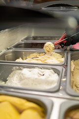 Female hand with scoop takes ice cream from the fridge. Fridge with ice cream. Pastry shop.