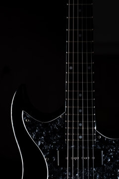 close up look of a black electric guitar isolated on black background. Vertical image