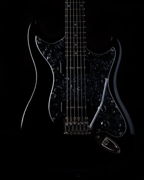 Close up look of an electric guitar, black background, vertical