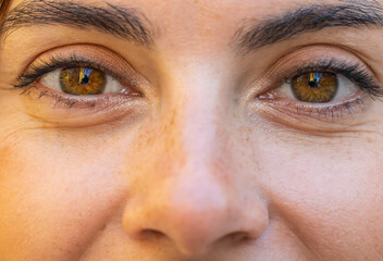 Extreme macro close-up portrait of face. Young adult beautiful pretty woman's eyes looking at camera. Brown eyes of teen girl female. Caucasian woman wide opening eyes, smiling. Laser correction