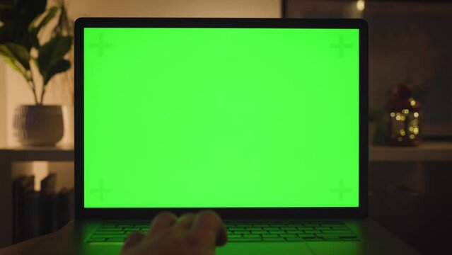 Man scrolling on laptop, laptop green screen mockup, home office
