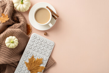 Obraz na płótnie Canvas Cozy fall workplace concept. Top view with keyboard, comfy brown knitted sweater, fresh coffee, saucer, pattypans, acorn, cinnamon, maple leaves on soft beige background. Empty space for text or ads