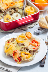 Casserole with potatoes, sausage and colorful bell pepper, on plate, vertical