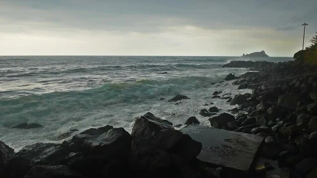 Waves hitting the shore on overcast rainy stormy day. Cyclops Coast, Sicily, near the town of Acireale