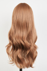 Naklejka premium Natural looking dark blonde wig on white mannequin head. Long fair hair cut on the plastic wig holder isolated on white background